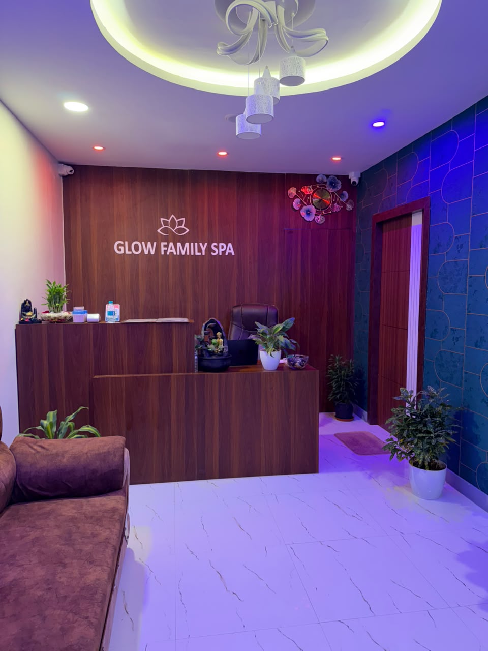 Vertical fluted walnut panels and illuminated lotus reception desk at Glow Spa Kalaburagi