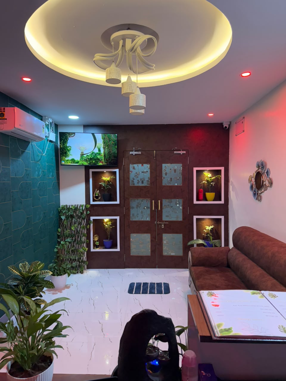 Circular halo cove ceilings and crystal chandelier welcome lounge at Glow Spa